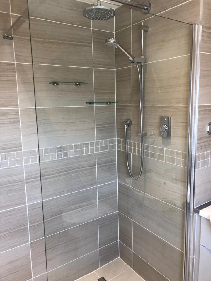 Walk-in shower enclosure with striped wood-effect tiles and a mosaic band