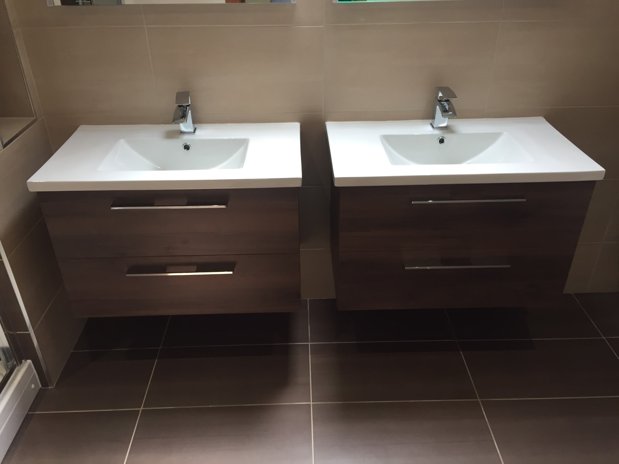 Twin wall-hung basin vanities in a dark wood finish on large-format floor tiles